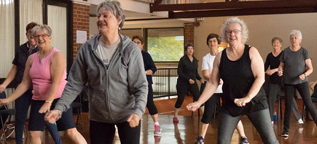 women smiling and exercising together in a community hall