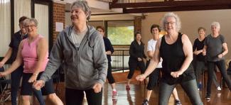 women smiling and exercising together in a community hall