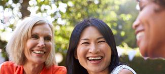 three women of different ages and cultural backgrounds together smiling